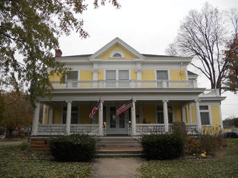 Picture of large yellow house with white trim